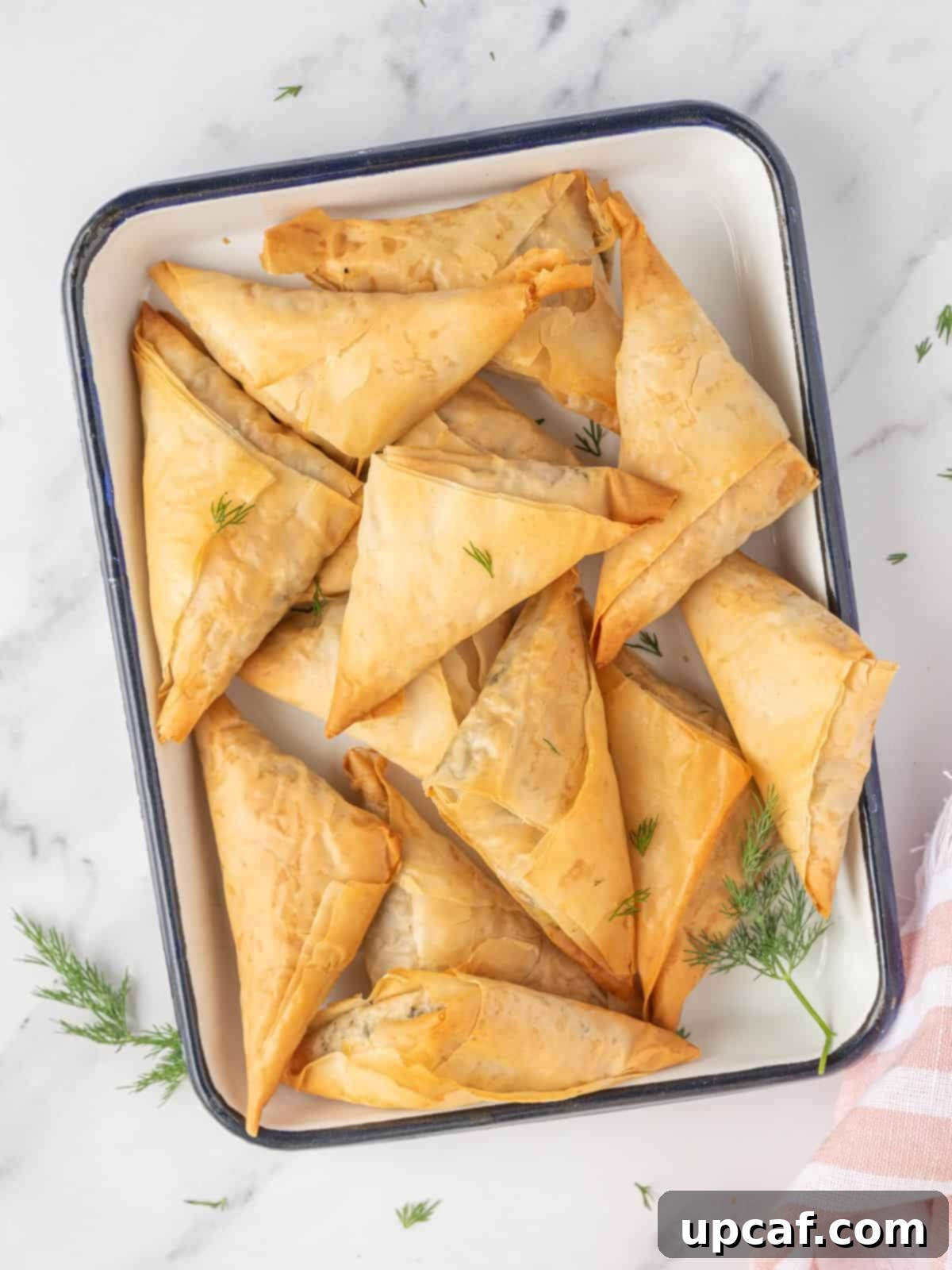 Quick & Easy Spanakopita Bites 2 Golden brown spinach and feta triangles arranged beautifully on a platter, ready to be served as an appetizer or part of a main meal.