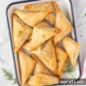 Quick & Easy Spanakopita Bites 11 Spinach and feta triangles on a platter.
