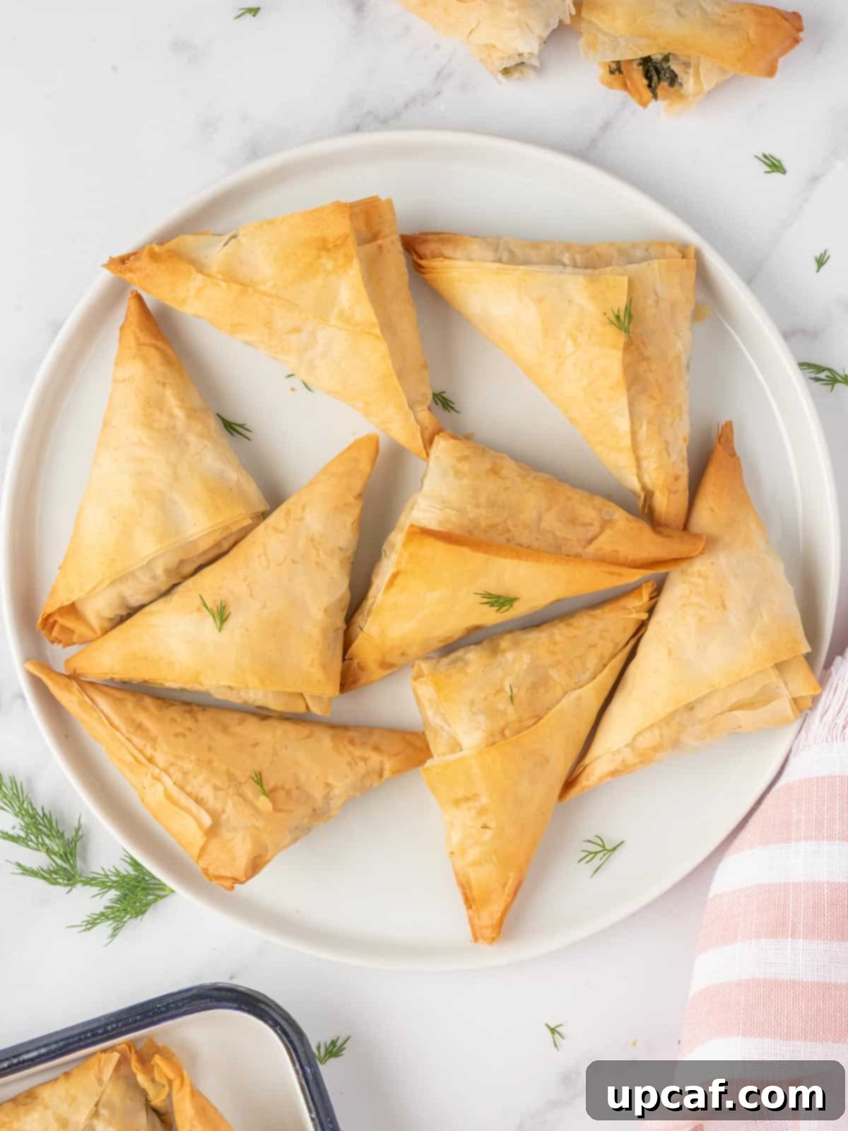 Quick & Easy Spanakopita Bites 8 A vibrant display of freshly baked spinach and feta triangles, beautifully golden and flaky, arranged on a serving platter.