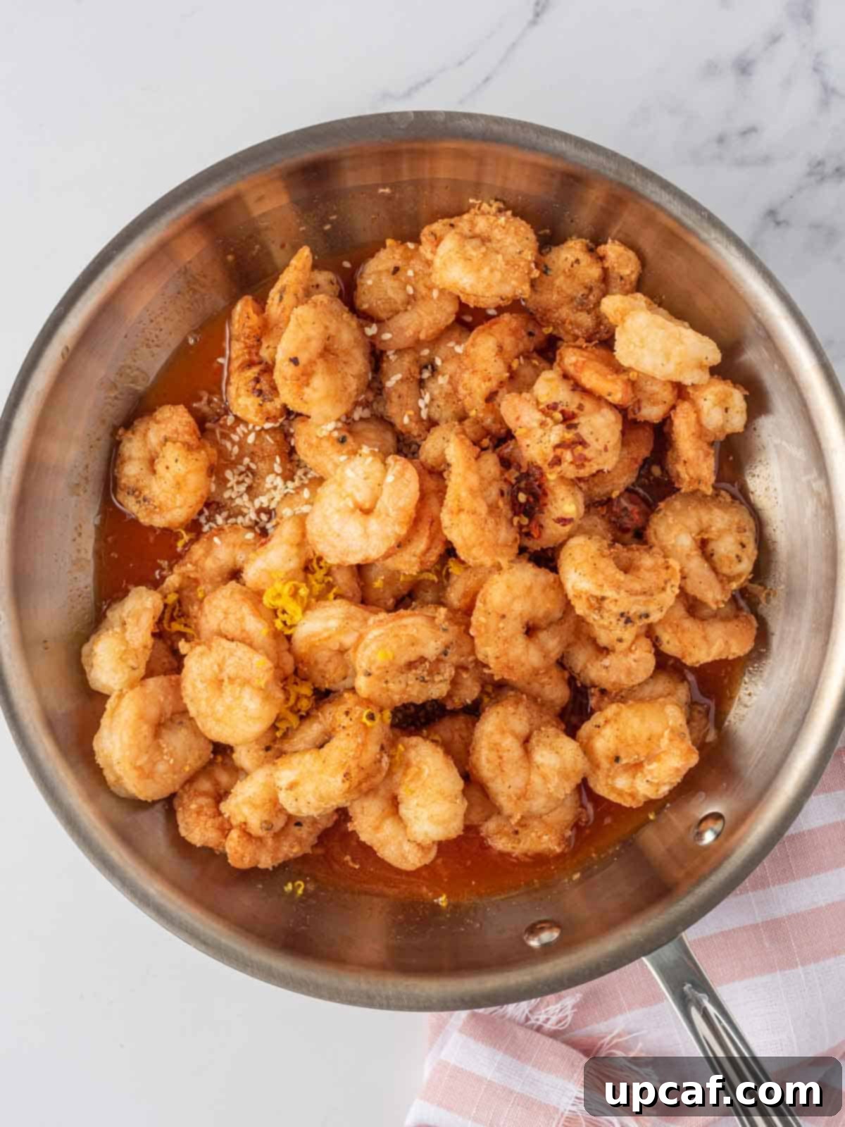 Blazing Burst Shrimp 7 Tossing spicy fried shrimp with the vibrant firecracker shrimp sauce in a pan for even coating.