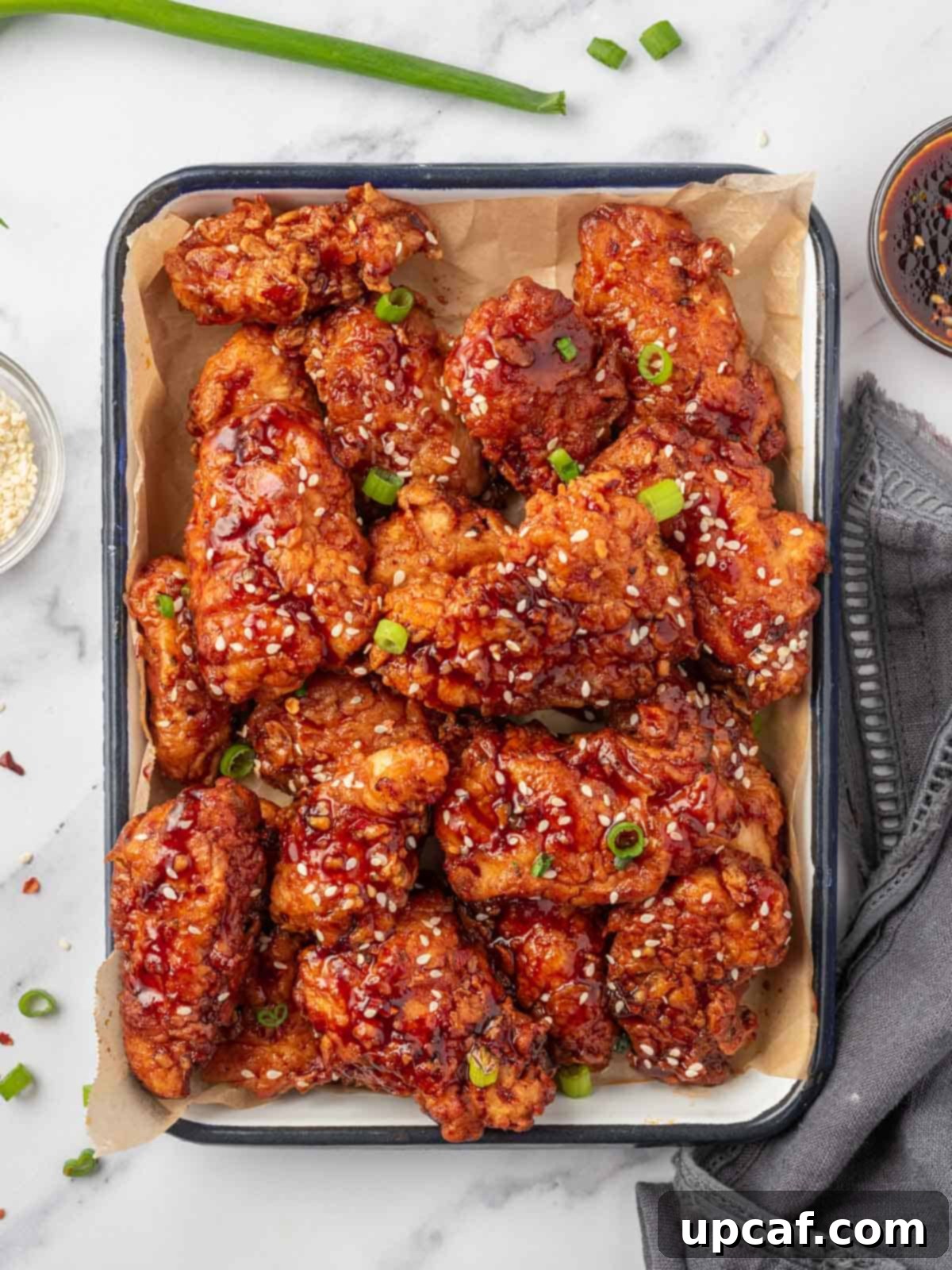 Addictive Crispy Korean Fried Chicken 2 Chicken tenders coated with gochujang sauce on a tray.