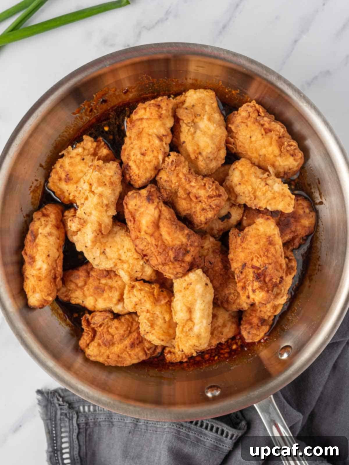 Addictive Crispy Korean Fried Chicken 9 Coating crispy chicken tenders with korean chicken sauce in a pan.
