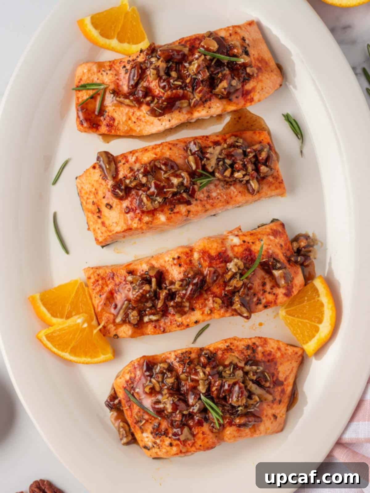 Caramelized Maple Pecan Salmon 2 A platter of beautifully prepared maple glazed salmon, garnished with fresh herbs and orange slices.