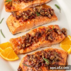 Caramelized Maple Pecan Salmon 9 Salmon with pecans and maple syrup on a platter with oranges as garnish.