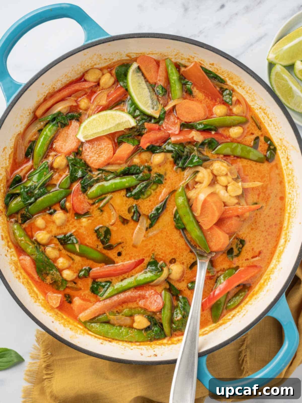 Vibrant Red Thai Plant-Based Curry 7 A large, inviting pot brimming with vibrant Thai red curry with vegetables, with a serving spoon gracefully resting inside, indicating that this delicious and aromatic meal is perfectly ready to be dished out and savored.
