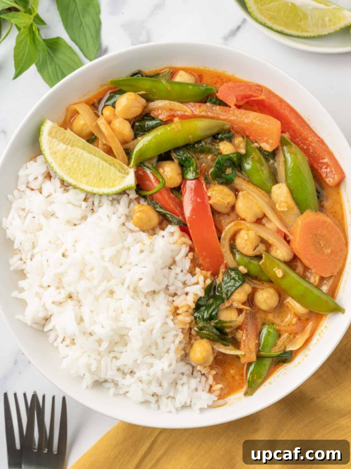 Vibrant Red Thai Plant-Based Curry 8 A beautifully presented bowl of fluffy white rice topped generously with creamy vegan red curry, vibrant vegetables, and fresh herbs, ready to be enjoyed as a wholesome and delicious meal.