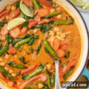 Vibrant Red Thai Plant-Based Curry 10 Serving red curry with vegetables from a pot, showcasing the rich texture and inviting aroma of the vegan dish.