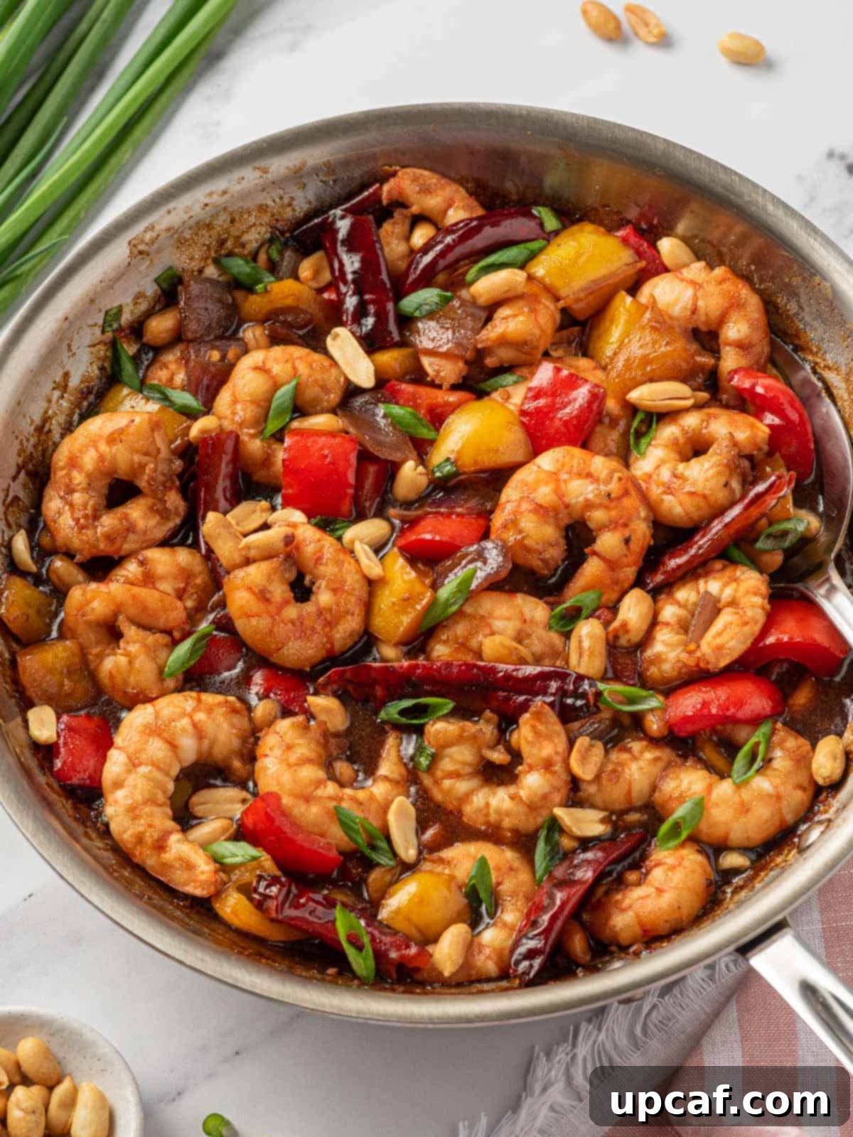 All the vibrant ingredients for Chinese shrimp, including the sauce, shrimp, and colorful vegetables, beautifully arranged in a skillet, ready for cooking.