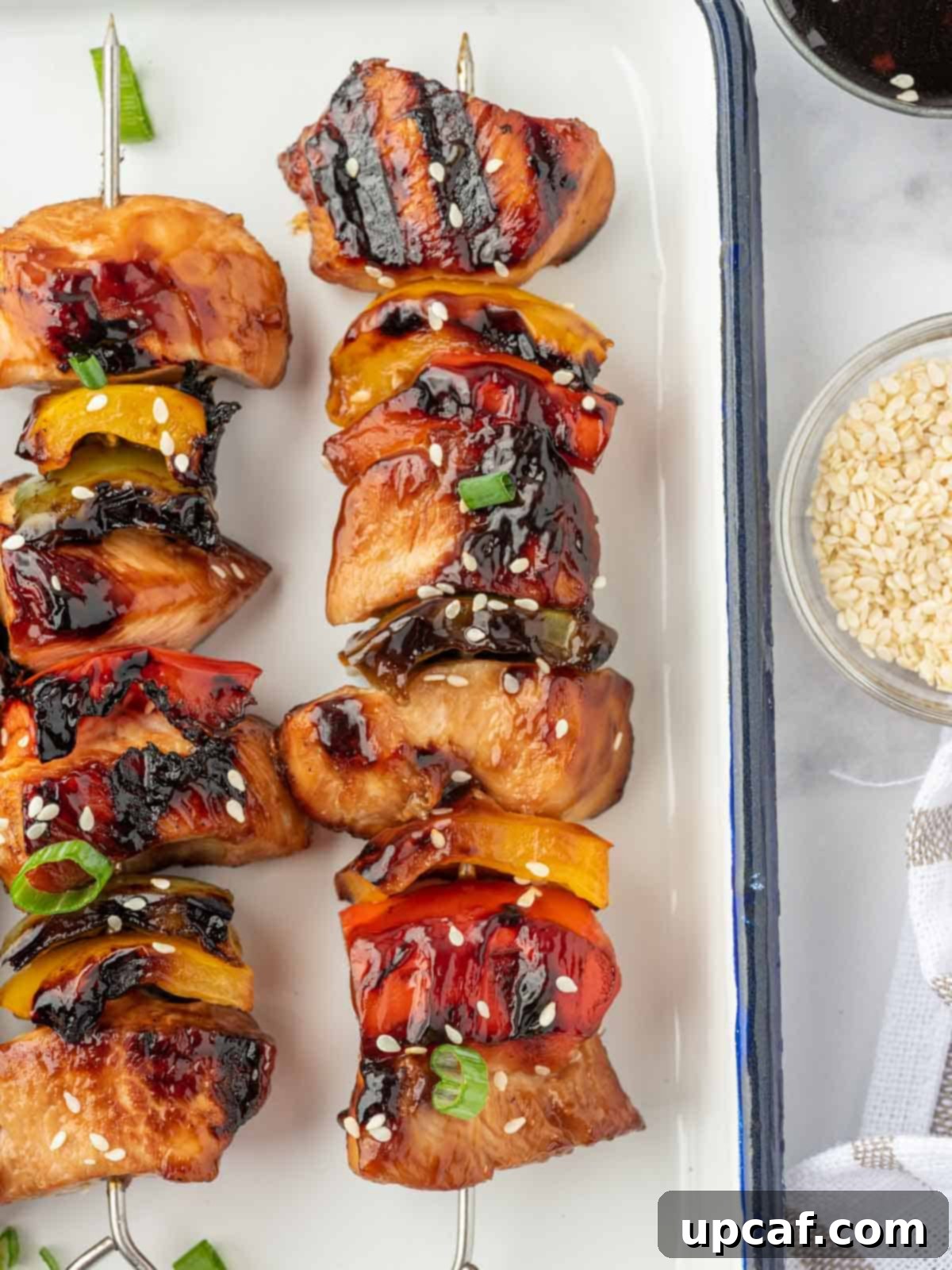 Sweet and Sticky Teriyaki Chicken Skewers 7 Close-up of a single grilled chicken teriyaki kabob on a platter, ready to be eaten.