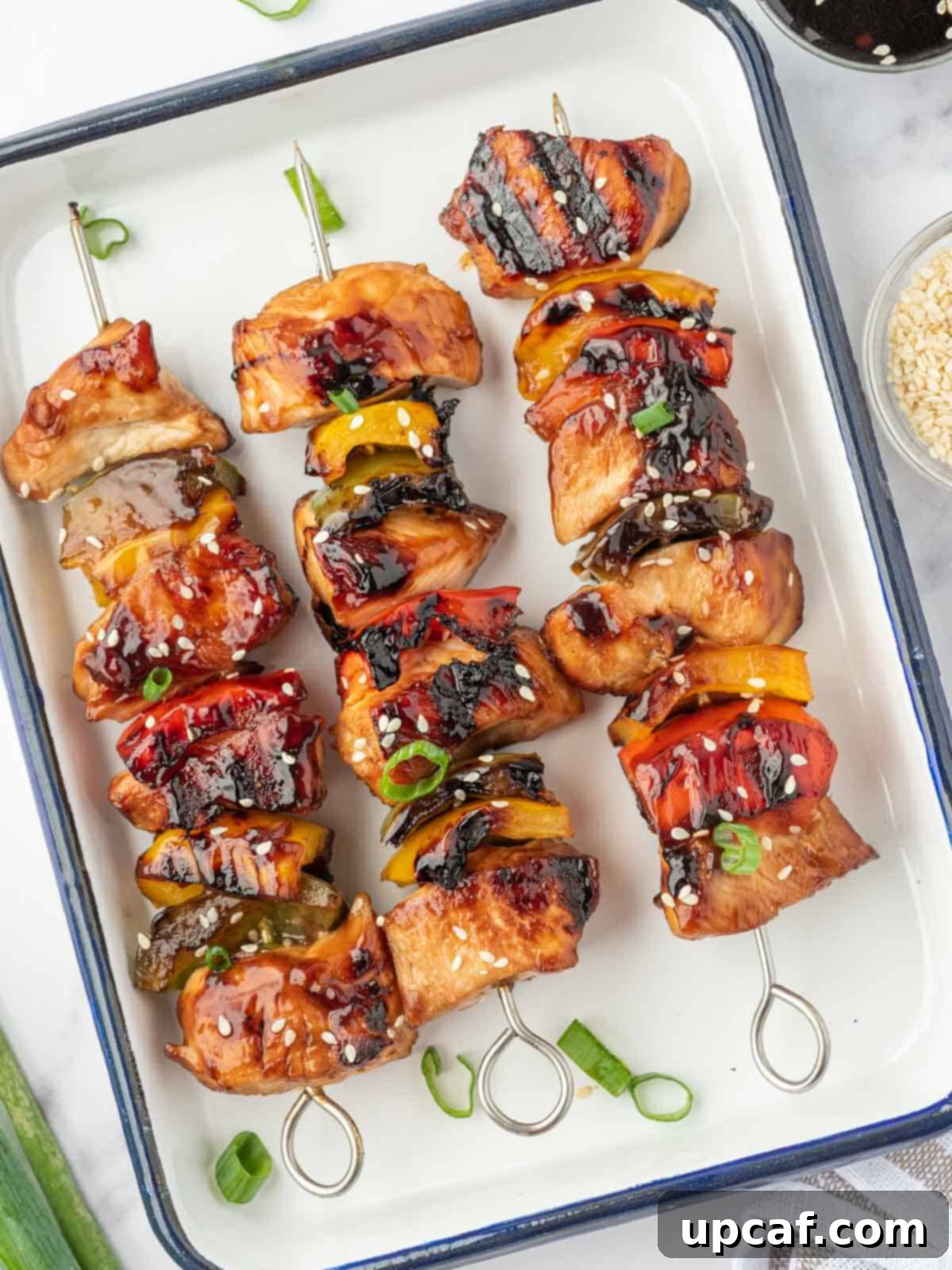 Sweet and Sticky Teriyaki Chicken Skewers 8 Marinated chicken teriyaki skewers arranged on a platter.