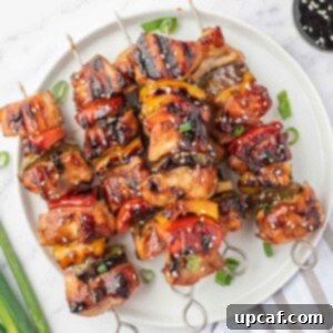 Sweet and Sticky Teriyaki Chicken Skewers 10 A pile of grilled chicken teriyaki skewers on a round platter.