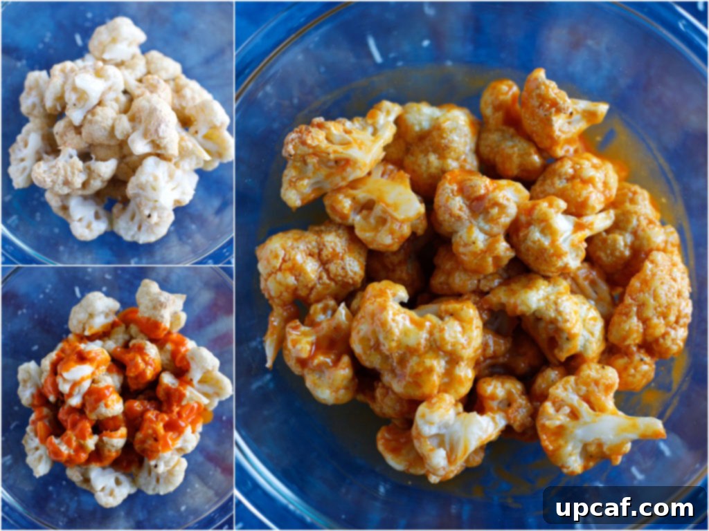 Baked cauliflower florets being tossed in a vibrant red buffalo sauce in a large bowl, demonstrating the sauce coating process.