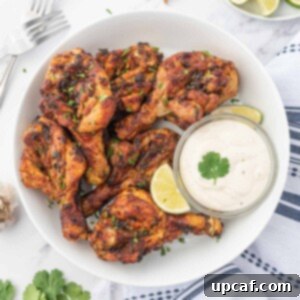 Air fryer butterfly chicken drumsticks on a plate with dipping sauce.