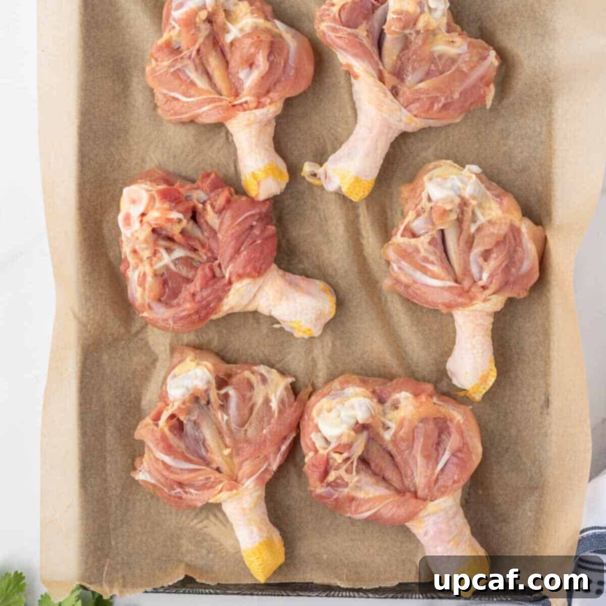 A close-up image showing how to butterfly chicken legs. A sharp knife is used to cut along the bone, spreading the meat flat like a wing for even cooking.