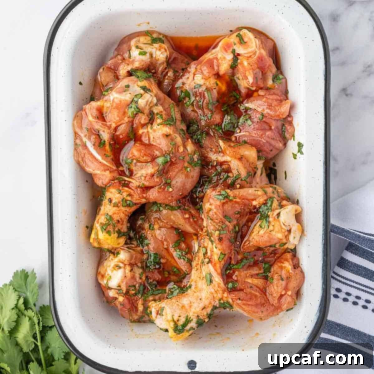 Butterflied chicken drumsticks marinating in a large bowl with the cilantro lime sauce, ready for air frying.