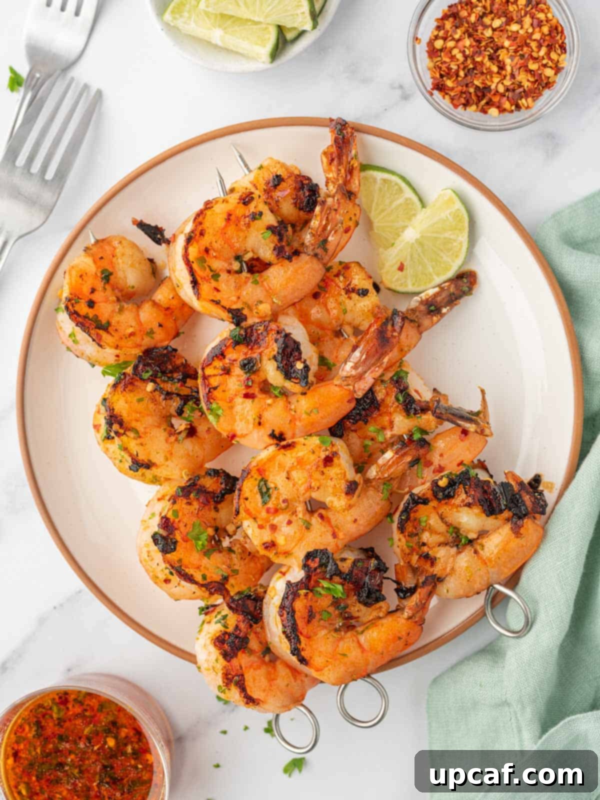 Zesty Garlic Shrimp Skewers 6 Garlic shrimp skewers on a plate with forks on the side.