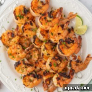 Zesty Garlic Shrimp Skewers 9 Honey lime shrimp skewers stacked on a plate with lime wedges.