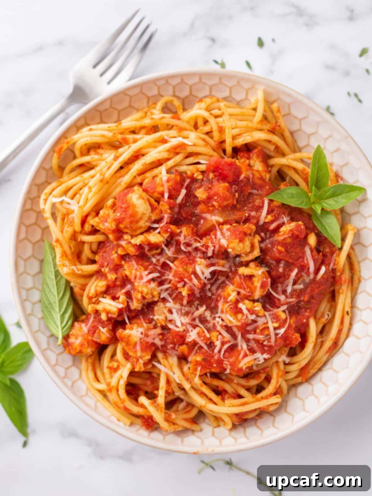 Hearty Chicken Ragu with Spaghetti 2 A bowl of healthy chicken bolognese garnished with fresh basil.