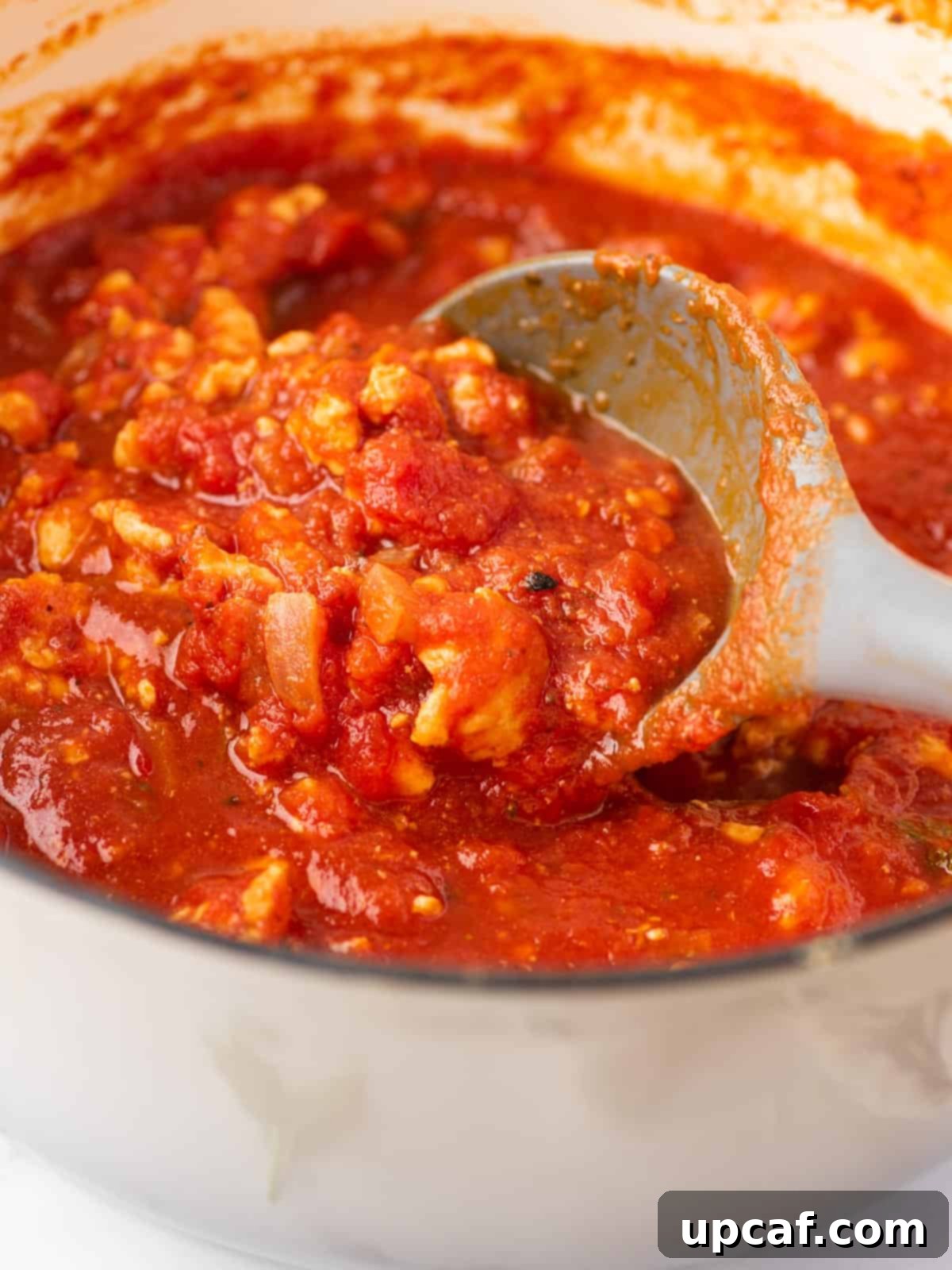 Hearty Chicken Ragu with Spaghetti 7 Spaghetti sauce with chicken in a saucepan being stirred with a spoon.