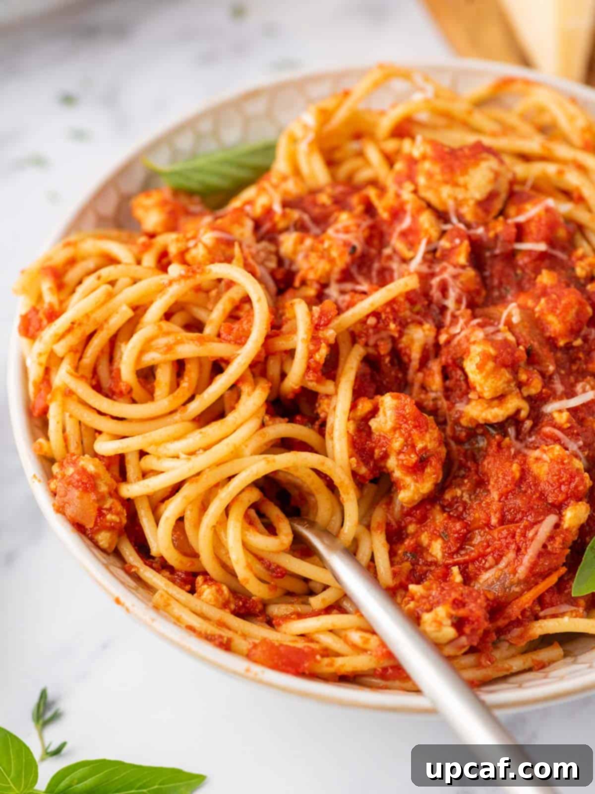 Hearty Chicken Ragu with Spaghetti 8 Closeup of a fork in a bowl of ground chicken bolognese.