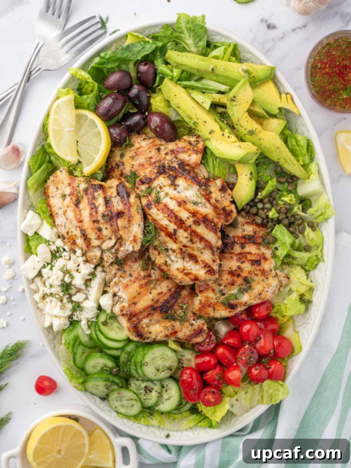 A large platter with grilled chicken greek salad.