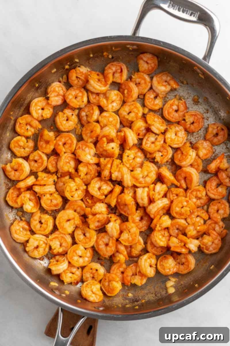 Close-up of shrimp being sautéed in a hot pan, turning pink as it cooks.
