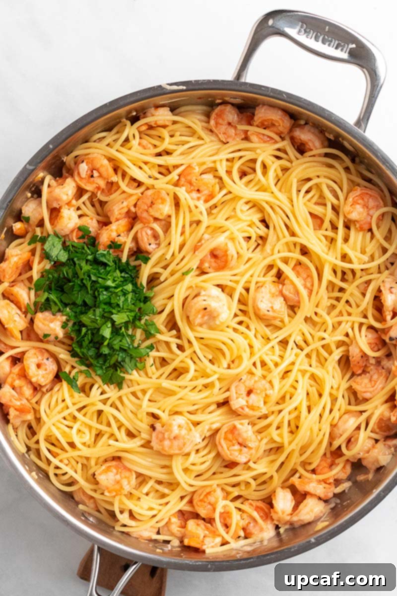 Garlic Parmesan Shrimp Spaghetti in a skillet, freshly tossed and garnished with parsley, ready to serve.
