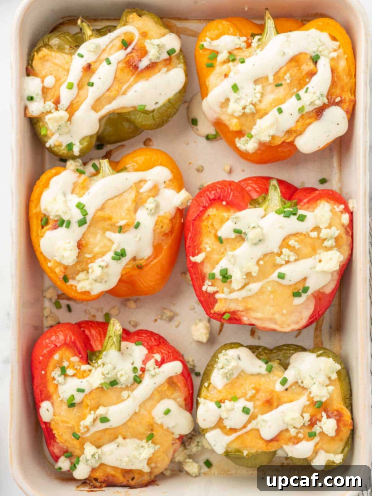 A baking tray filled with keto stuffed peppers with chicken, generously topped with melted cheese and blue cheese crumbles.