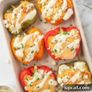 Healthy chicken stuffed peppers topped with ranch and crumbled blue cheese in a baking dish.