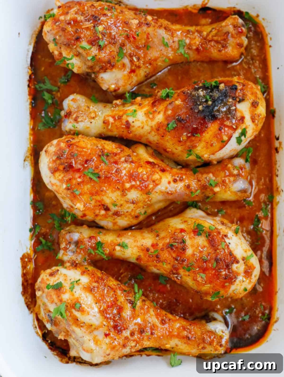 Finished easy chicken drumsticks recipe on a platter for serving, garnished with fresh parsley.