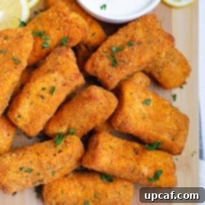 Crispy salmon fish fingers on a board with dipping sauce.