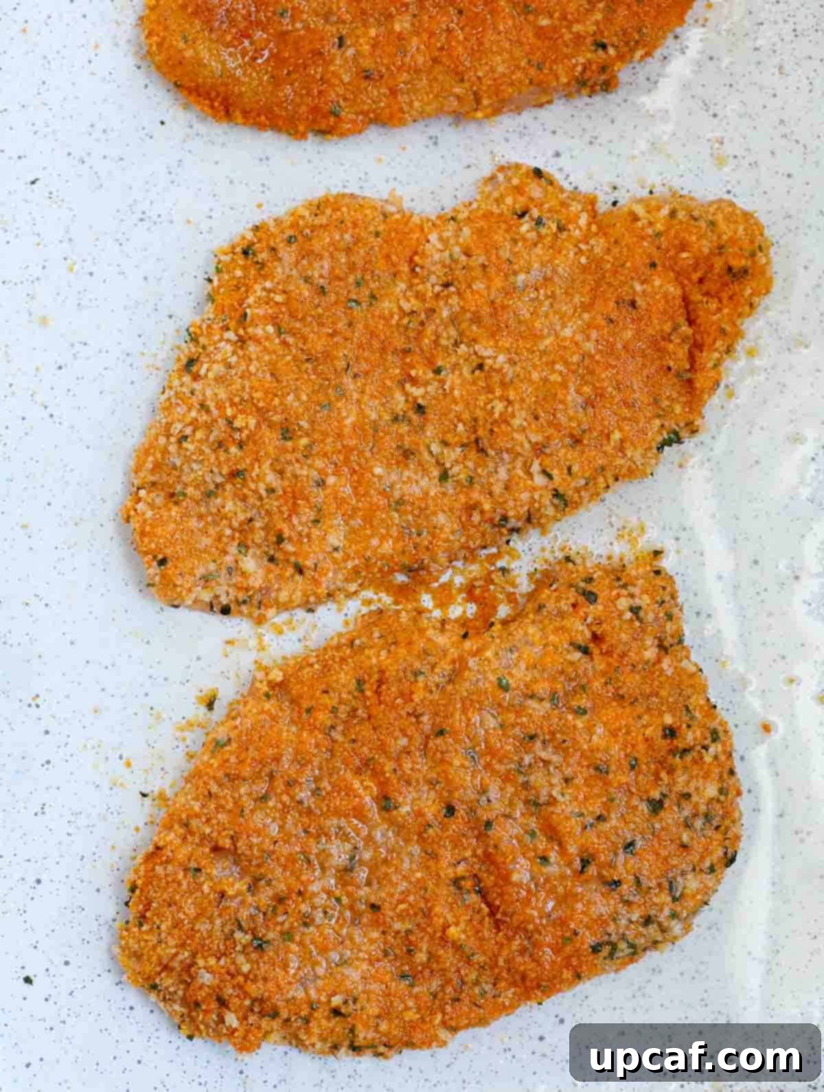 Baked chicken cutlets waiting to be garnished with parsley.