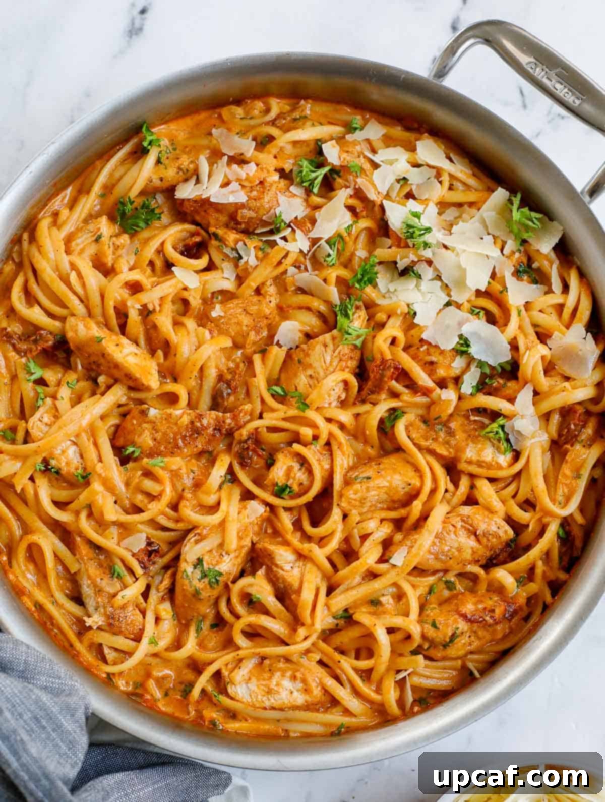 A skillet of creamy spicy chicken pasta, garnished with fresh herbs.
