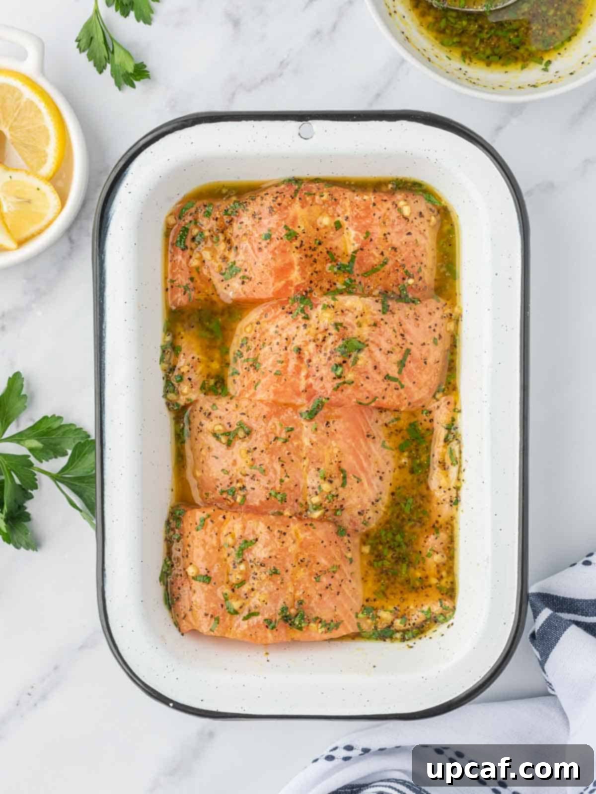 Zesty Lemon Pepper Salmon 5 Salmon fillets being coated with lemon pepper marinade in a bowl.