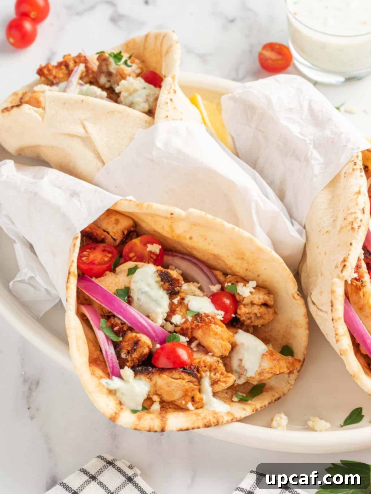Authentic chicken gyros on a platter with fresh garnishes.