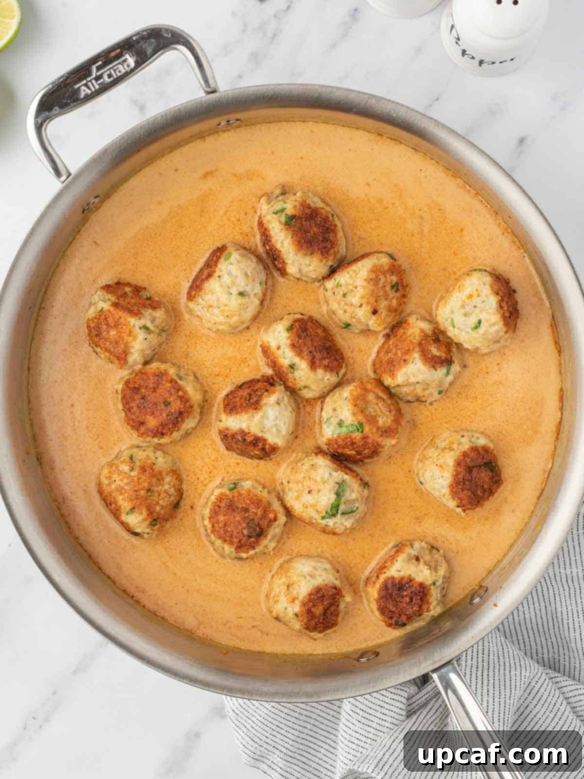Thai Spiced Chicken Meatballs 7 Perfectly browned Thai chicken meatballs gently simmering in a creamy, vibrant coconut curry sauce in a skillet, absorbing all the rich flavors.