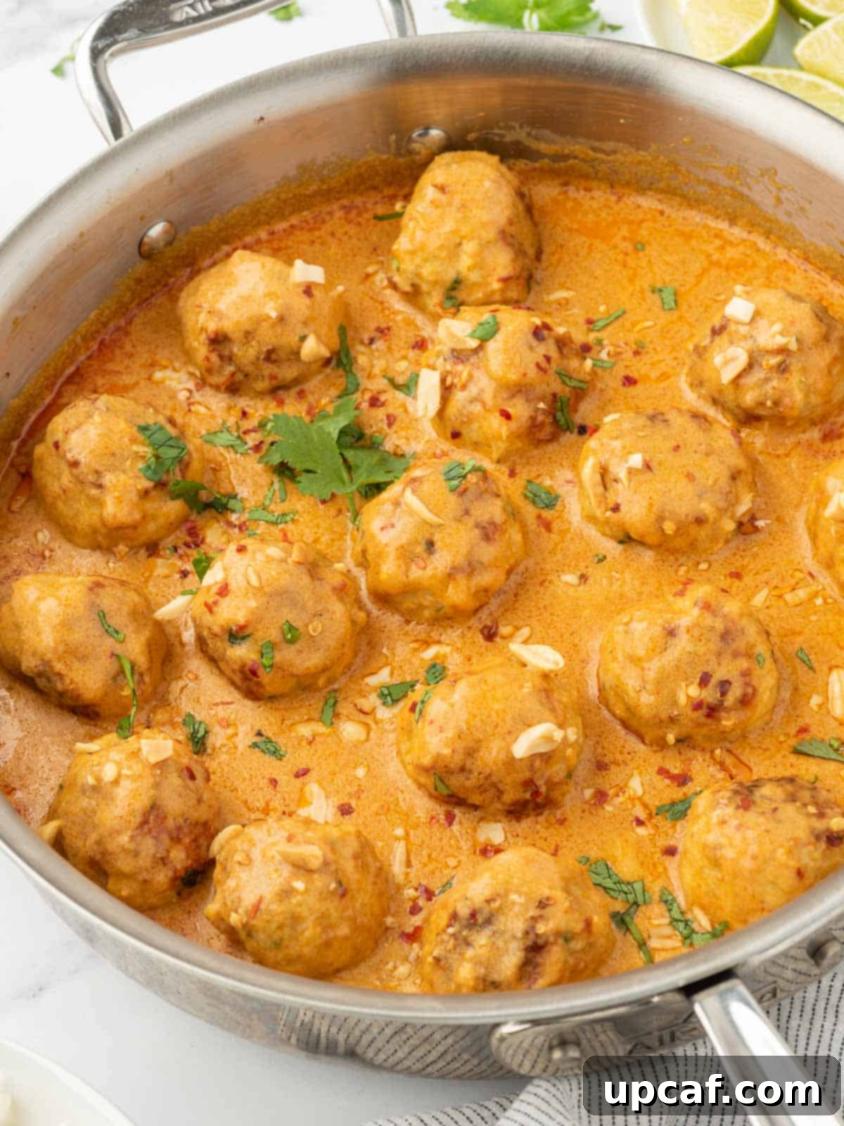 Thai Spiced Chicken Meatballs 8 A close-up shot of creamy Thai chicken meatballs with curry sauce in a rustic skillet, garnished with fresh cilantro, ready to be enjoyed.