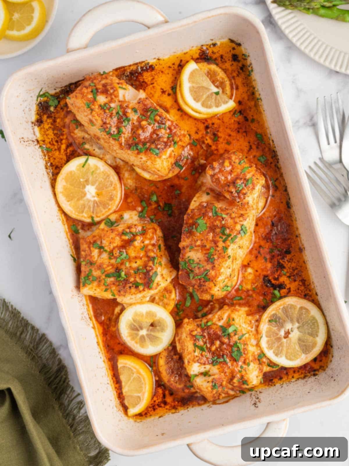 Cajun Garlic Butter Baked Cod 2 A baking dish with the best baked cod topped with lemon slices.