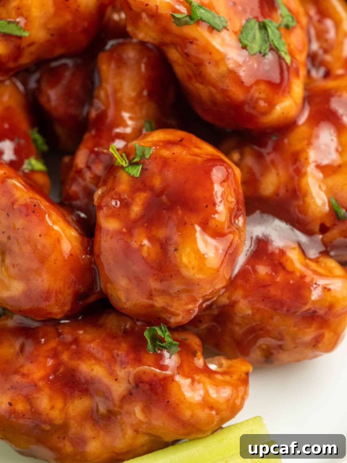 A tantalizing close-up of a pile of BBQ-coated chicken bites, showing their sticky, glossy texture and inviting appearance.
