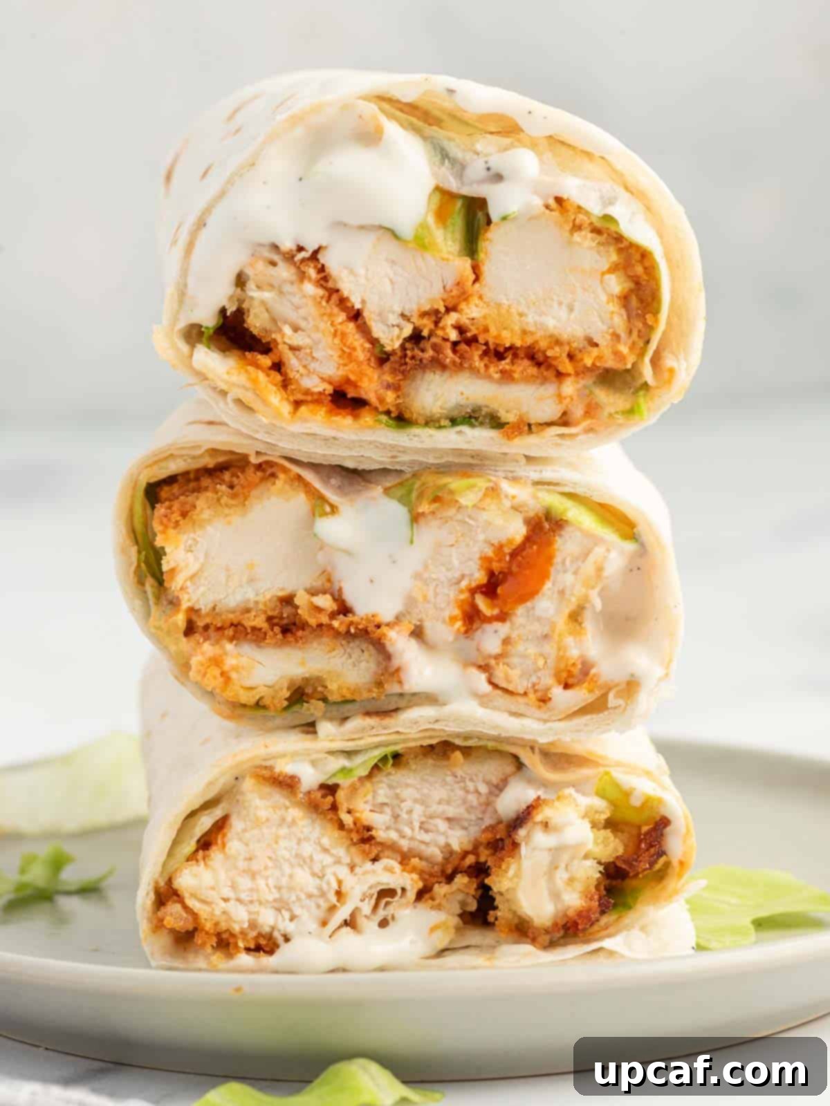 Crispy Buffalo chicken wrap sliced into pieces and stacked on a plate, revealing its layered ingredients.