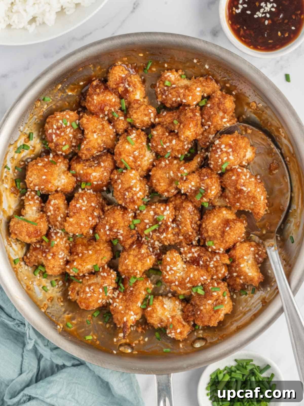 Sesame Glazed Cauliflower Poppers 8 A pan of stick sesame cauliflower bites with a spoon and bowls of garnish.