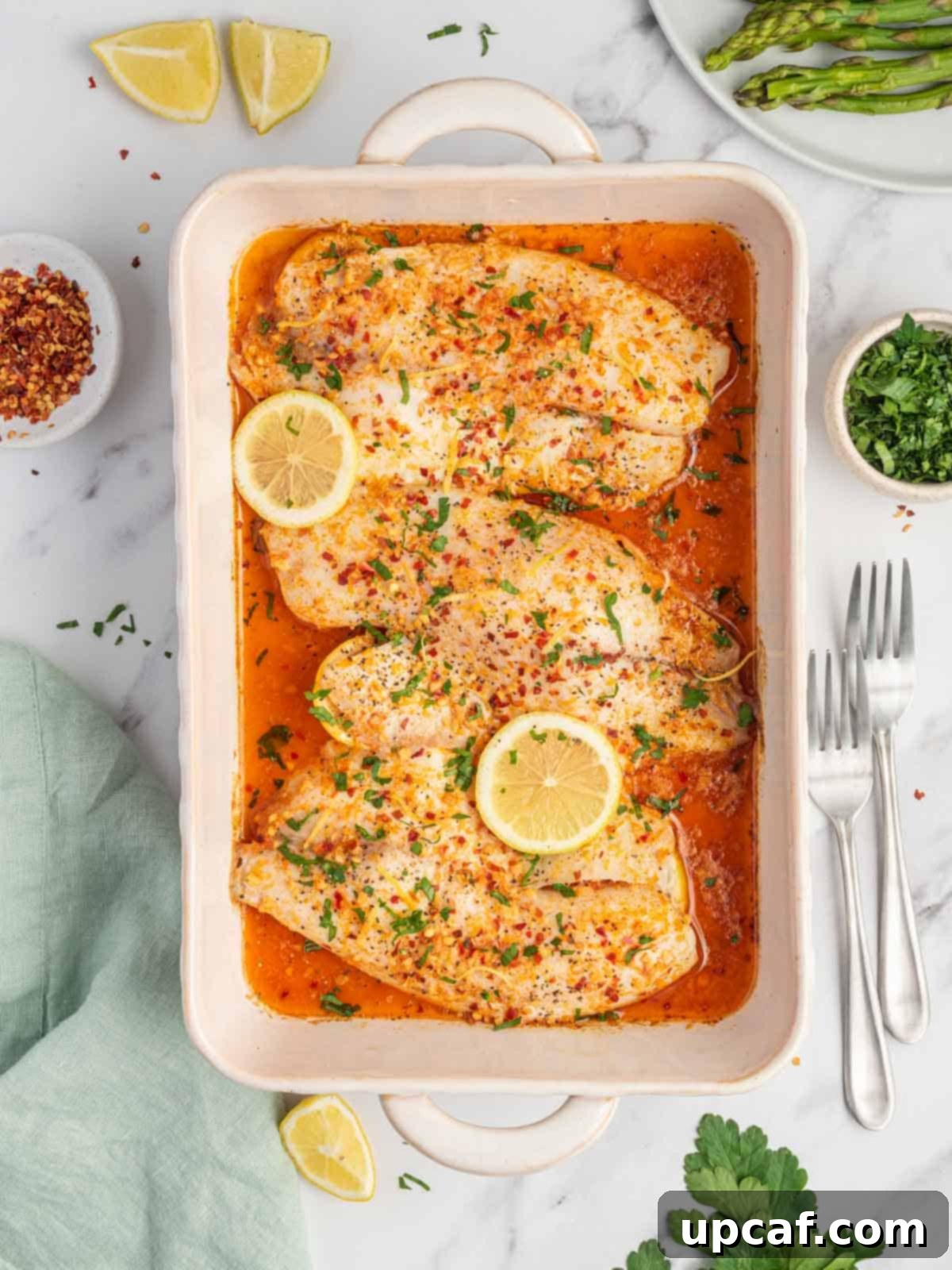 Finished easy oven baked tilapia recipe in a baking dish with forks.