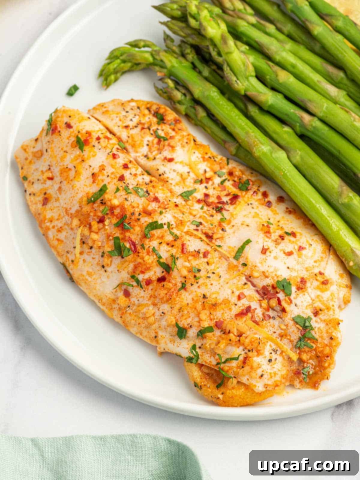 Easy baked tilapia recipe on a plate with asparagus.