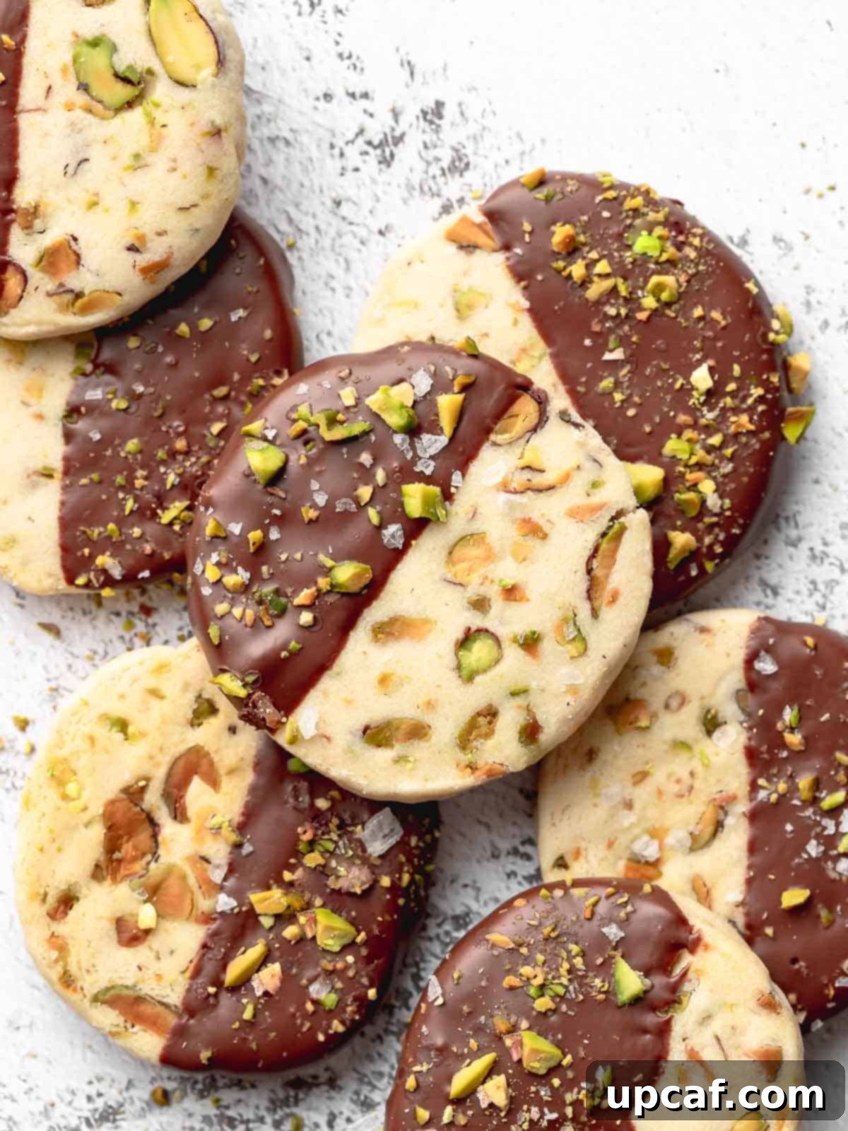 A plate of pistachio shortbread cookies dipped in chocolate.