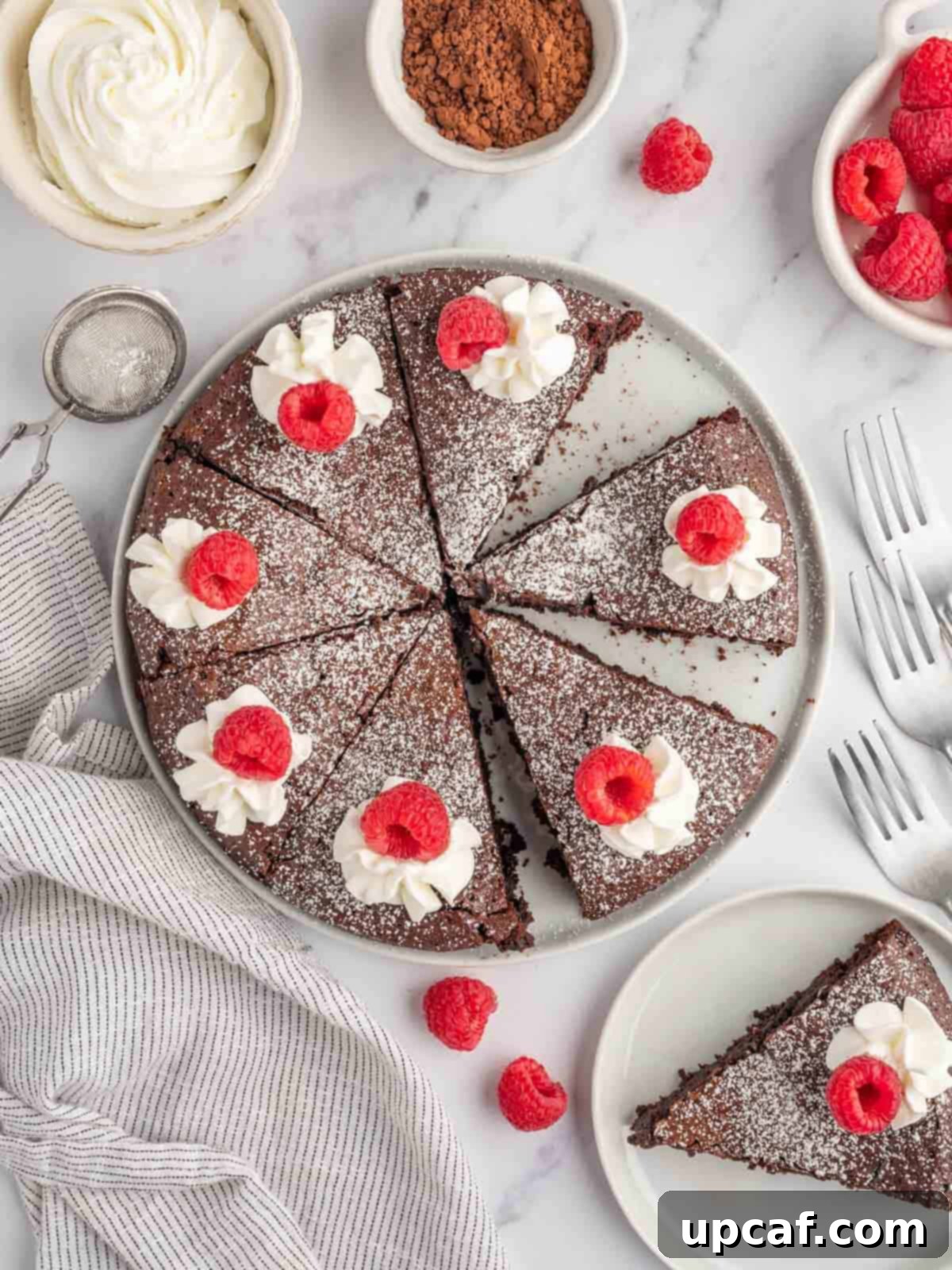 Velvet Chocolate Torte 2 A flourless chocolate cake with a slice on a serving plate, garnished with raspberries and powdered sugar.