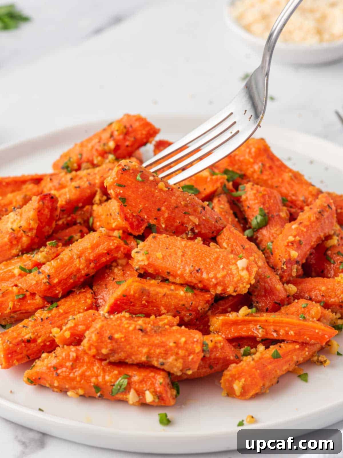 A fork picks up a oven roasted carrot, highlighting its tender texture.