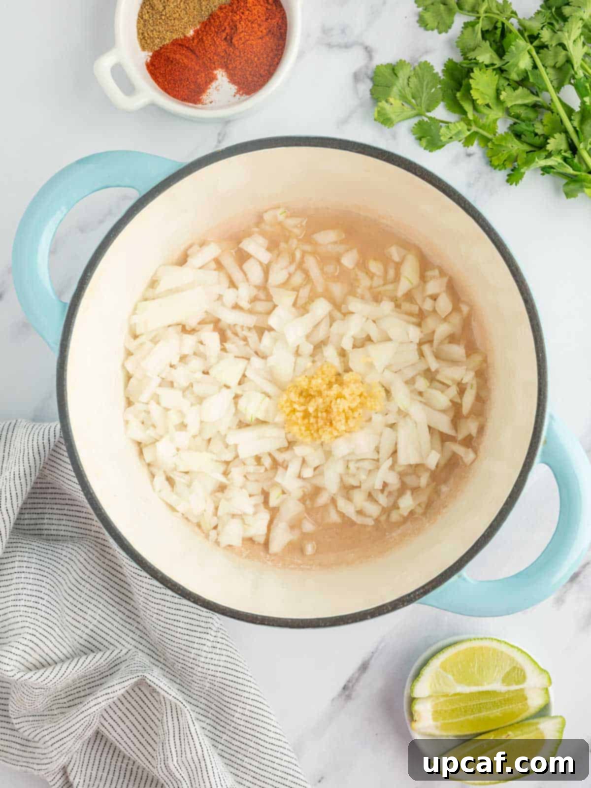 Hearty Plant-Based Lentil Chili 4 Chopped yellow onions and minced garlic gently sautéing in shimmering olive oil within a sturdy cast iron Dutch oven on a stovetop.