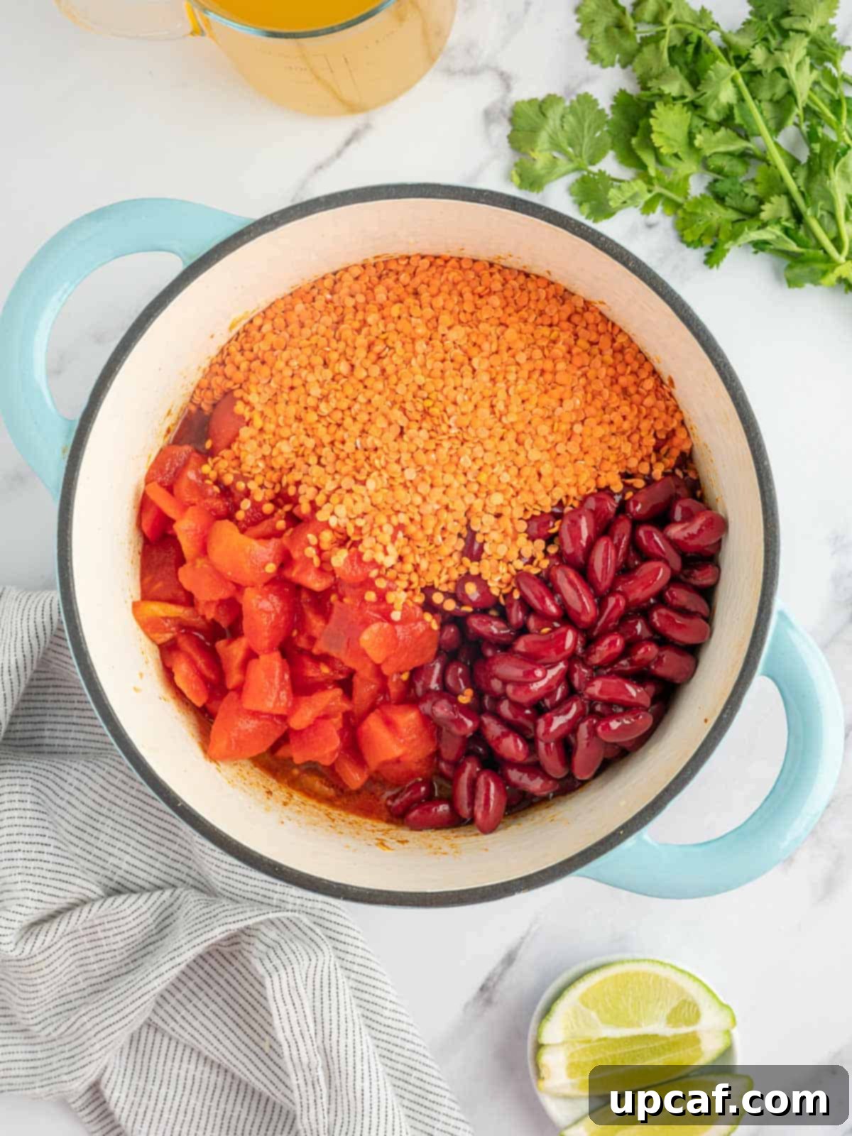 Hearty Plant-Based Lentil Chili 5 Various vegan chili ingredients, including rinsed lentils, kidney beans, diced tomatoes, and tomato sauce, being combined in a large pot, ready for simmering.