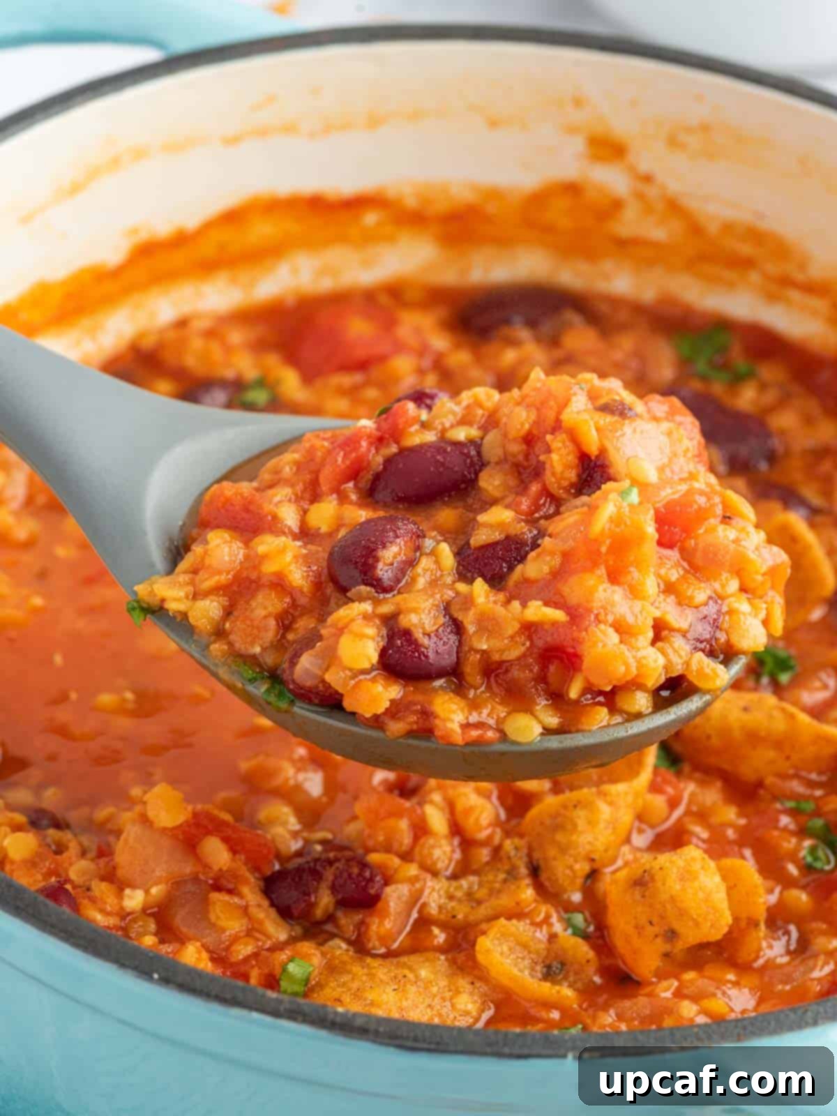 Hearty Plant-Based Lentil Chili 7 A large serving spoon scooping a generous portion of thick, rich vegan bean chili from a Dutch oven, showcasing the blend of lentils and kidney beans.