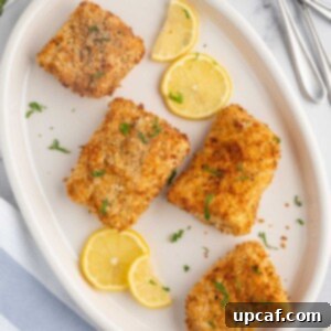 A plate of crispy air fryer cod with lemon slices.